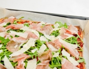 Pizza mit Rohschinken, Rucola und Parmesan